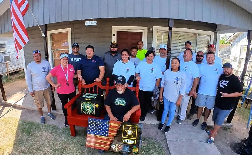 The Armored Painting crew and volunteers with the Operation Veteran Paint Project recipient outside his freshly painted home