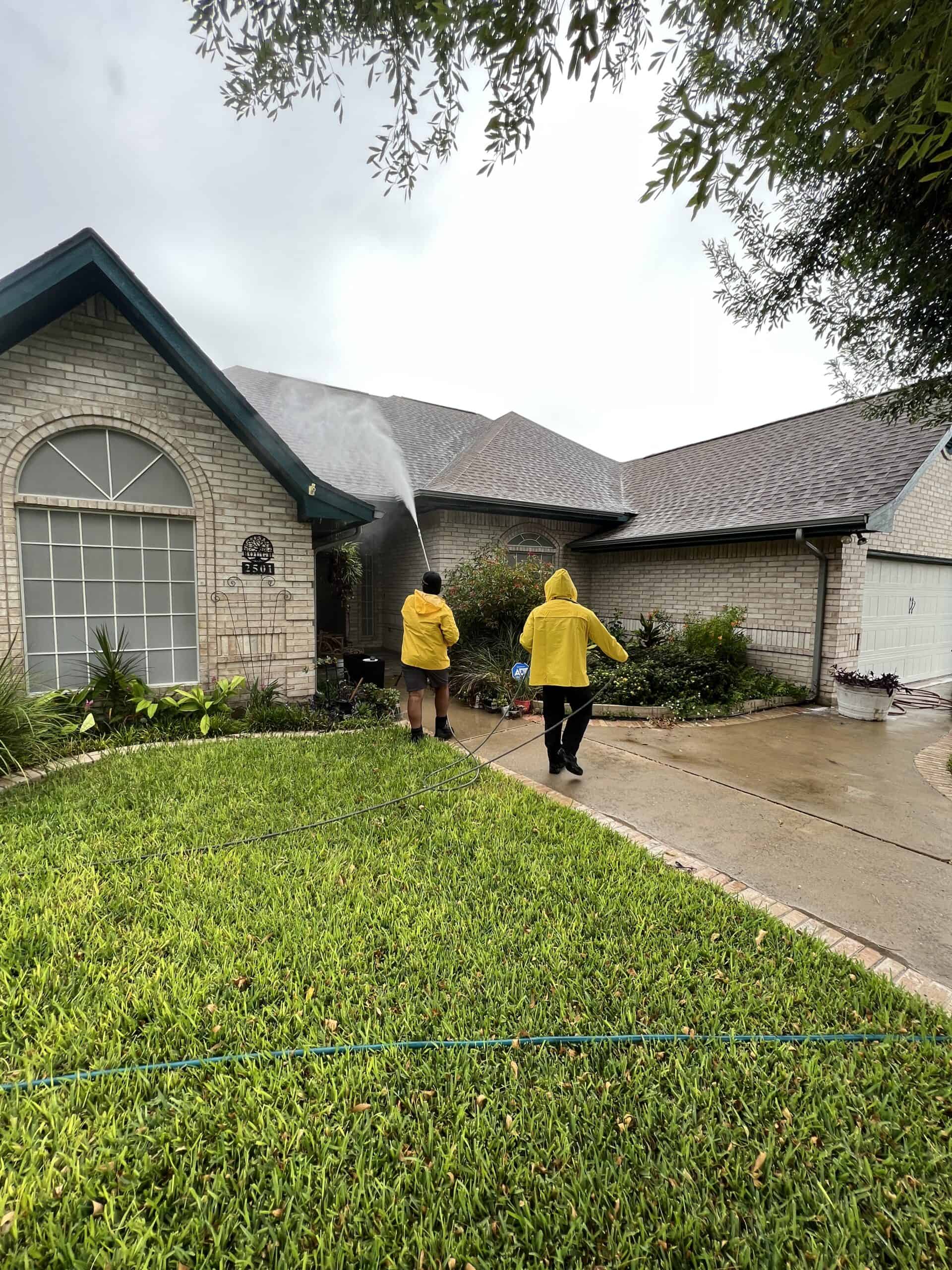 Crew in rain gear pressure washing a home exterior