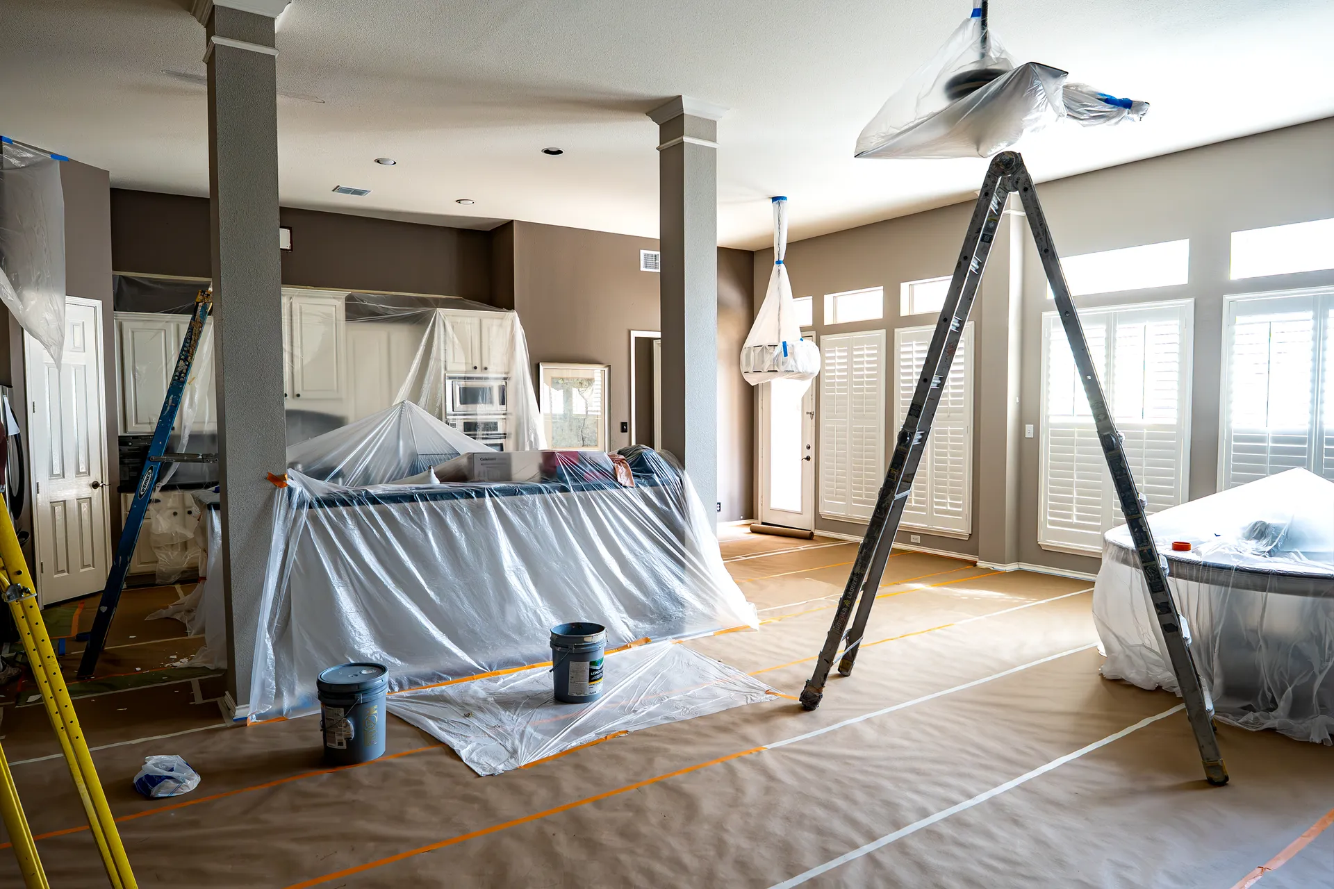 Open living area masked with plastic sheeting during an interior repaint